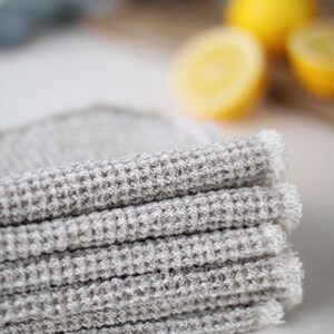 May include: A stack of gray waffle weave kitchen towels with a frayed edge.