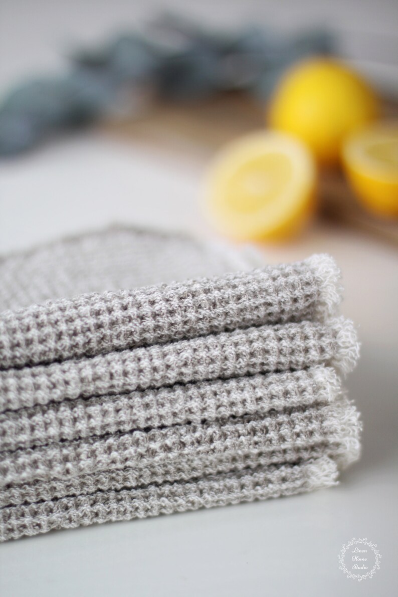 May include: A stack of gray waffle weave kitchen towels with a frayed edge.