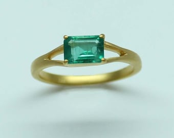 May include: A gold ring with a green emerald gemstone.