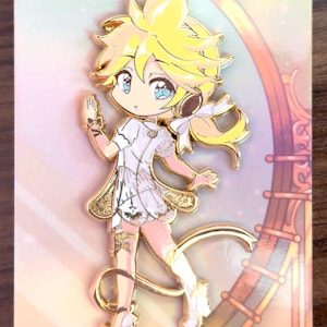 May include: Gold-colored enamel pin featuring a cartoon character with blonde hair, wearing a white dress and headphones. The character is standing on a pink and gold background.