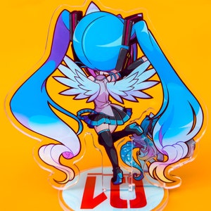 Puede incluir: Una figura de anime azul y blanca con alas, de pie sobre una base redonda con el texto "LJ" en rojo. El personaje tiene el pelo largo azul y lleva un atuendo blanco y azul.
