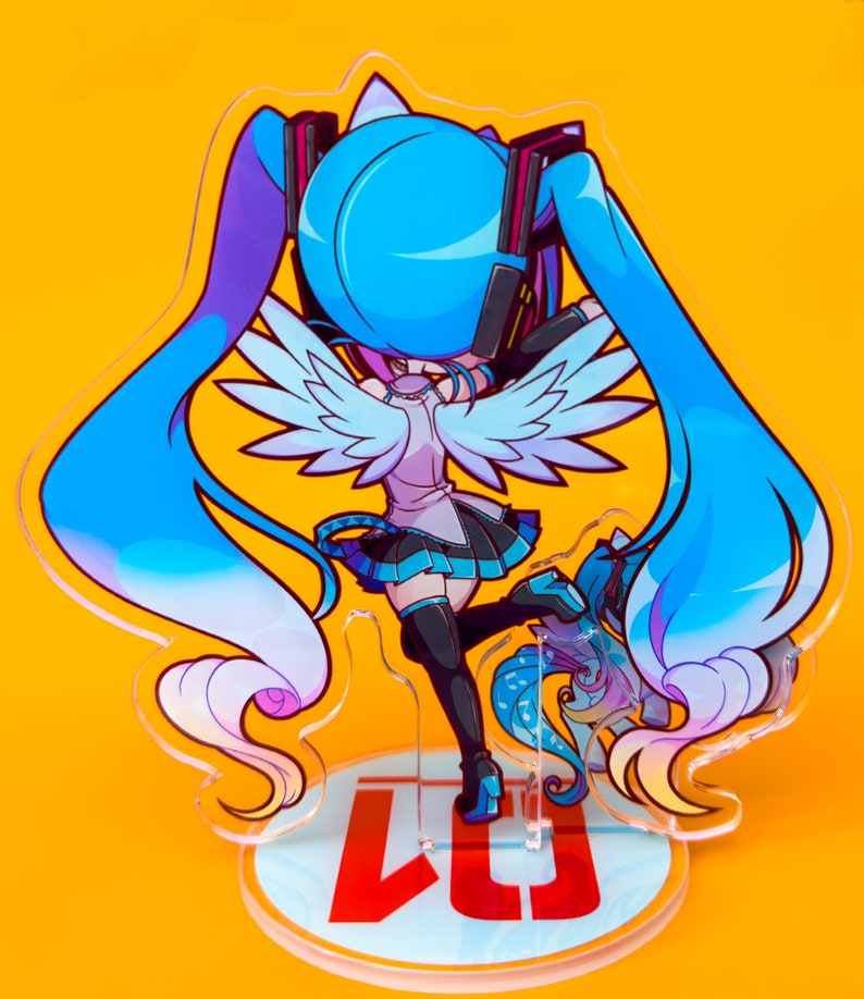 Puede incluir: Una figura de anime azul y blanca con alas, de pie sobre una base redonda con el texto "LJ" en rojo. El personaje tiene el pelo largo azul y lleva un atuendo blanco y azul.