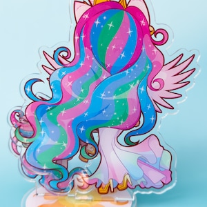 Puede incluir: Un soporte de acr&iacute;lico colorido con una representaci&oacute;n de dibujos animados de la Princesa Celestia de My Little Pony. El soporte es transl&uacute;cido y muestra al personaje con un vestido rosa, azul y verde con una corona dorada y alas. La base del soporte es un sol amarillo.