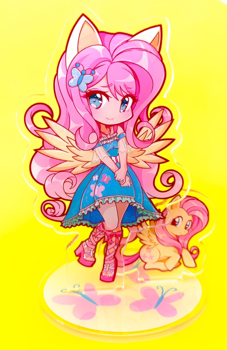 May include: A pink and yellow anime-style character with wings and cat ears stands on a base with butterflies. The character is wearing a blue dress with a white collar and white sleeves. The character has pink hair and blue eyes. The character is holding a small pink and yellow pony with wings.