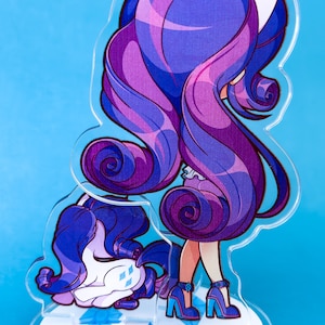 May include: A purple and blue cartoon character with long hair and white cat ears. The character is standing on a white base with blue diamond shapes. The character is wearing a white dress and blue shoes.