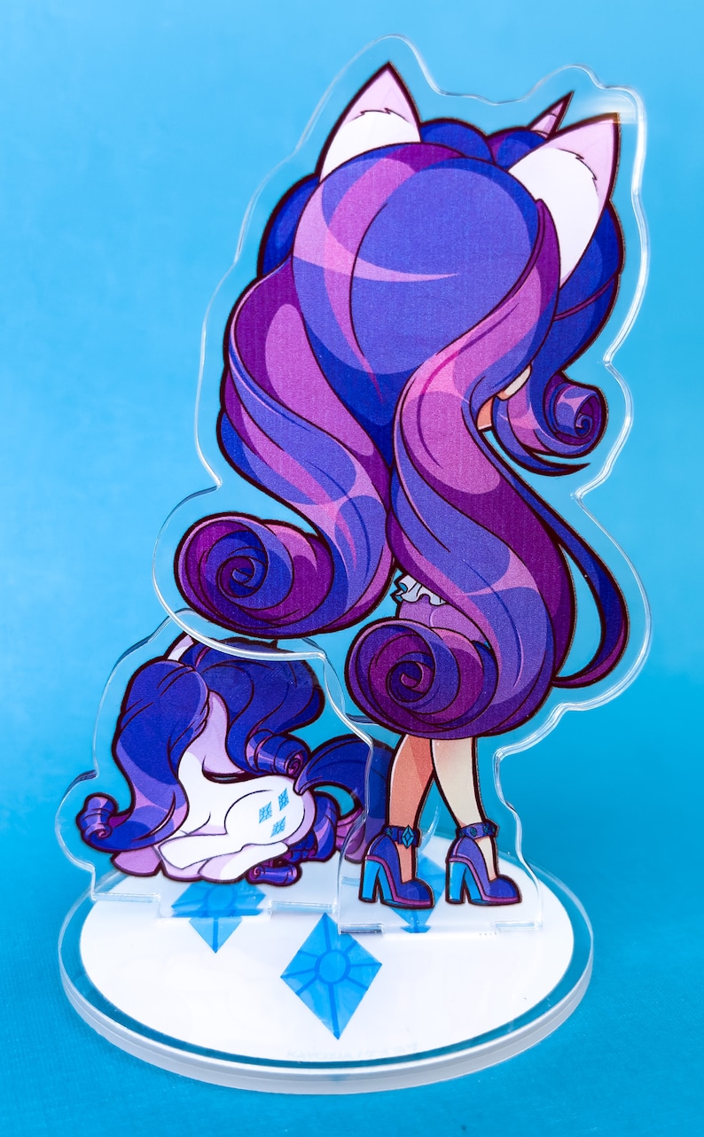 May include: A purple and blue cartoon character with long hair and white cat ears. The character is standing on a white base with blue diamond shapes. The character is wearing a white dress and blue shoes.