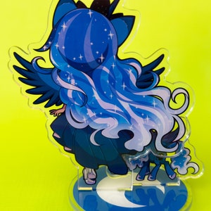 Puede incluir: Un personaje de estilo anime azul y morado con alas y una base de media luna. El personaje tiene el pelo largo y fluido con estrellas incrustadas. El personaje est&aacute; de pie sobre una base de media luna con un fondo azul.