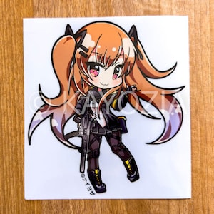 May include: A sticker featuring an anime-style character with orange hair in pigtails, holding a rifle. The character wears a black outfit with yellow accents. The sticker has a white background and the text "©ケイヨウ" in Japanese.