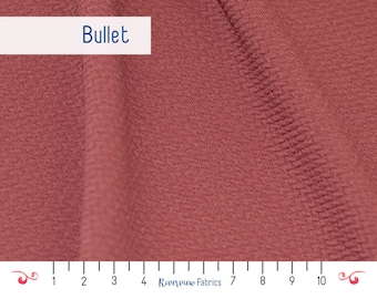 May include: Close-up of a textured, reddish-brown fabric with the word "Bullet" printed on a white label. A ruler is visible at the bottom of the image, with markings from 1 to 10.