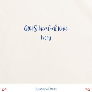 May include: Cream-colored fabric with the text "GOTS Interlock Knit Ivory" in dark blue script. The words "Riverview Fabrics" are at the bottom in a similar font. The background is a solid, off-white color.