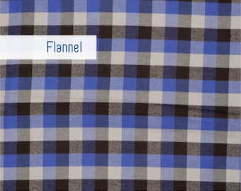 May include: Blue, black, and gray plaid flannel fabric. The fabric has a classic checkered pattern with squares of varying sizes. The word "Flannel" is displayed on a white rectangle. A ruler is at the bottom of the image.
