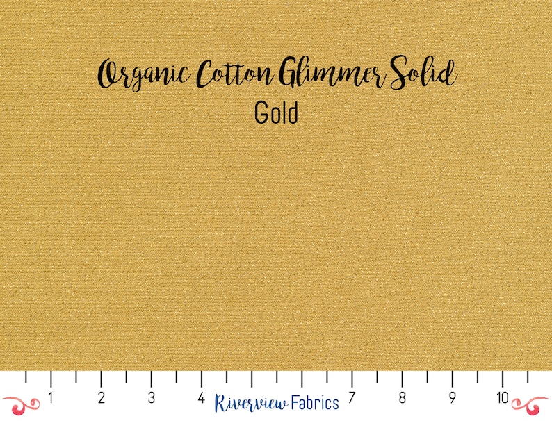 May include: A close-up of a gold organic cotton fabric with a subtle shimmer. The fabric is labeled "Organic Cotton Glimmer Solid Gold".