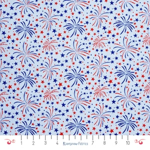 Puede incluir: Tela azul claro con un patrón repetido de fuegos artificiales y estrellas rojas y azules. Los fuegos artificiales están estilizados con líneas rojas y azules, y las estrellas son pequeñas y dispersas. La tela está marcada con una regla y el texto "Riverview Fabrics".