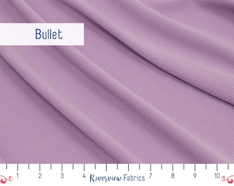 May include: A close-up of a soft, textured fabric in a light purple color. The fabric is draped and shows its texture. A ruler is visible at the bottom of the image, with markings from 1 to 10 inches.