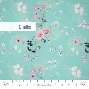 Puede incluir: Una tela turquesa con un estampado floral. El diseño presenta flores rosas y blancas, hojas verdes y la palabra "Challis" en un recuadro blanco. La tela tiene un tacto delicado y aireado, adecuada para ropa o decoración del hogar.
