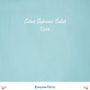 Pode incluir: Um tecido azul claro liso com o texto "Cotton Supreme Solids Cove" em branco. O tecido é de cor lisa e parece ser de algodão. O logotipo da Riverview Fabrics está na parte inferior.