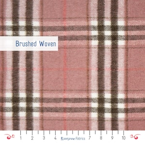 May include: A close-up of a brushed woven fabric with a plaid design. The fabric has a dusty rose base, crossed by white, brown, and light pink lines. The text "Brushed Woven" is displayed on a white rectangle.