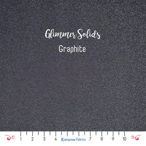 May include: A close-up of a dark gray fabric with a textured surface. The fabric is labeled "Glimmer Solids Graphite".