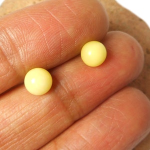May include: Two small, round, yellow pearl earrings.