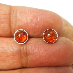 May include: A pair of silver stud earrings with round amber stones.