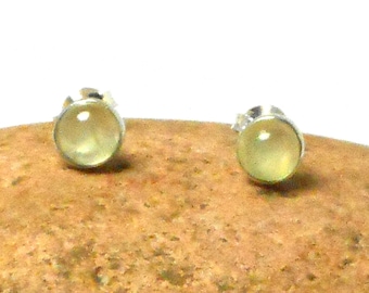 May include: A pair of silver stud earrings with round, light green gemstones.