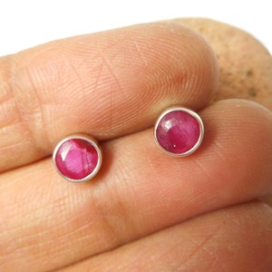 Könnte beinhalten: Ein Paar silberne Ohrstecker mit runden rosafarbenen Rubinen.