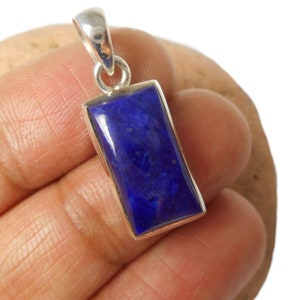 May include: A silver pendant with a rectangular lapis lazuli stone. The stone is a deep blue color with white veins.