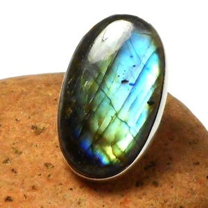 Könnte beinhalten: Ovaler Labradorit-Edelsteinring mit einer silbernen Fassung. Der Edelstein hat einen blauen, grünen und goldenen irisierenden Schimmer.
