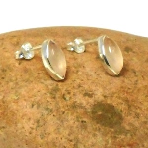 May include: A pair of silver earrings with light pink oval-shaped stones.