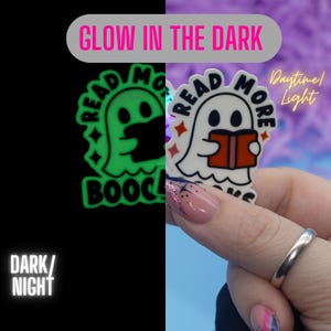 May include: A glow-in-the-dark sticker featuring a ghost holding a book with the text "Read More Books". The sticker glows green in the dark and is white in daylight.