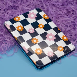 May include: A clear phone case with a black and white chequered pattern and pink and orange flowers.