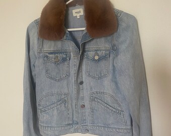 May include: A light blue denim jacket with a brown faux fur collar. The jacket has a button closure and two front pockets. The brand label "seed" is visible on the front of the jacket.
