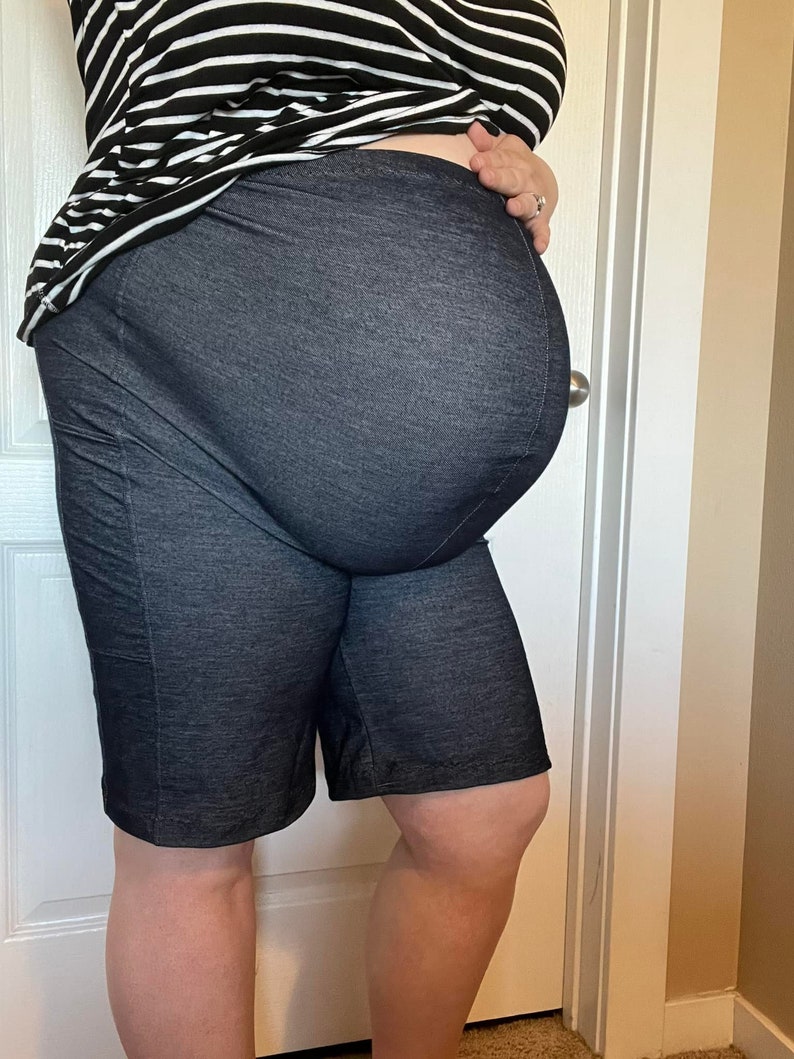 Puede incluir: Un par de pantalones cortos de mezclilla oscura con cintura el&aacute;stica. Los pantalones cortos son usados por una persona y est&aacute;n subidos alto en la cintura.