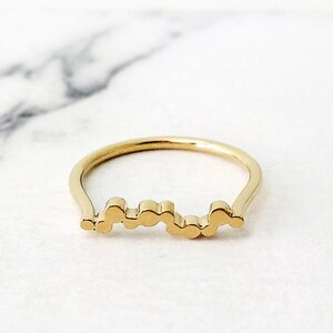 May include: A gold ring with a unique design featuring a series of connected circles.