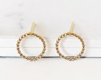 May include: A pair of gold-toned circle stud earrings with a twisted rope design.