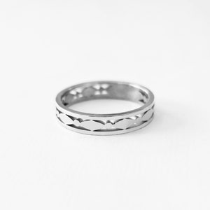 May include: A silver ring with a repeating pattern of cut-out shapes. The ring is circular and has a polished finish. The design features a series of elongated, diamond-like cutouts around the band, creating an openwork effect. The ring is set against a white background.