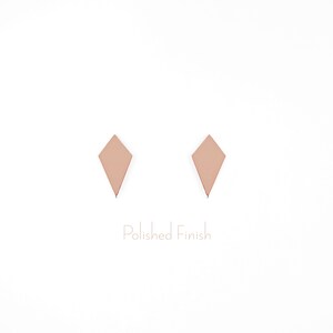 May include: A pair of rose gold diamond-shaped earrings with a polished finish.
