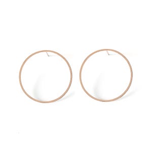 May include: A pair of rose gold hoop earrings with a simple circular design.