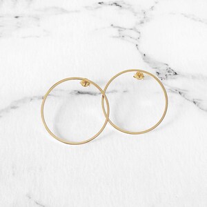 May include: A pair of gold hoop earrings. The earrings are simple and elegant, with a smooth, circular design.