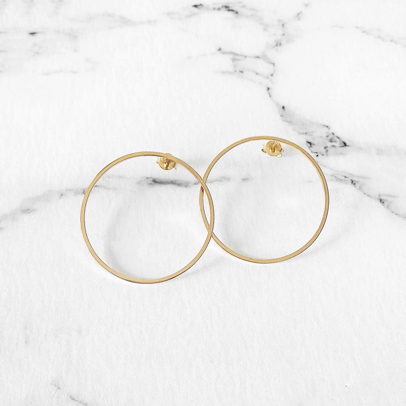 May include: A pair of gold hoop earrings. The earrings are simple and elegant, with a smooth, circular design.
