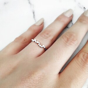 May include: A silver ring with a wavy design made of small circles.