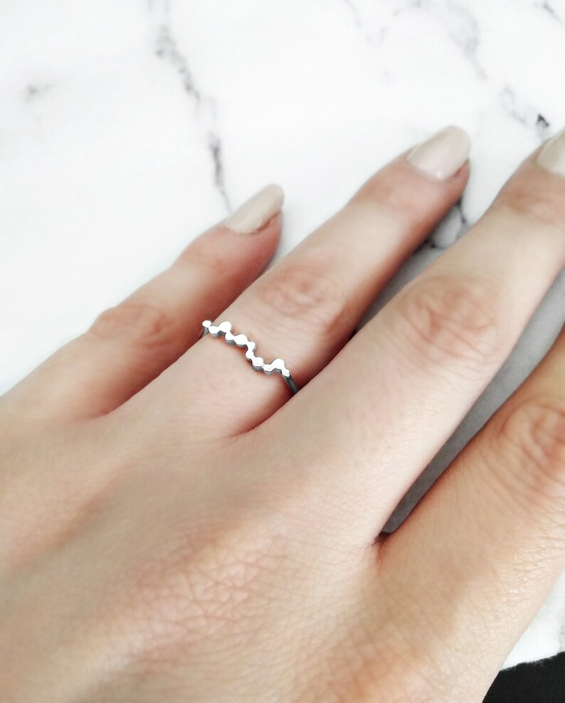 May include: A silver ring with a wavy design made of small circles.