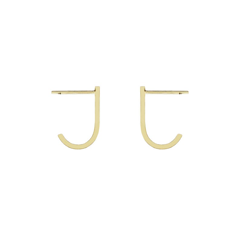 May include: A pair of gold-toned hoop earrings with a simple, minimalist design. The earrings are shaped like a 'J' and are made of a thin, delicate metal.