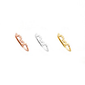 May include: Three delicate rings with a wavy design made of small circles. The rings are in gold, silver, and rose gold.