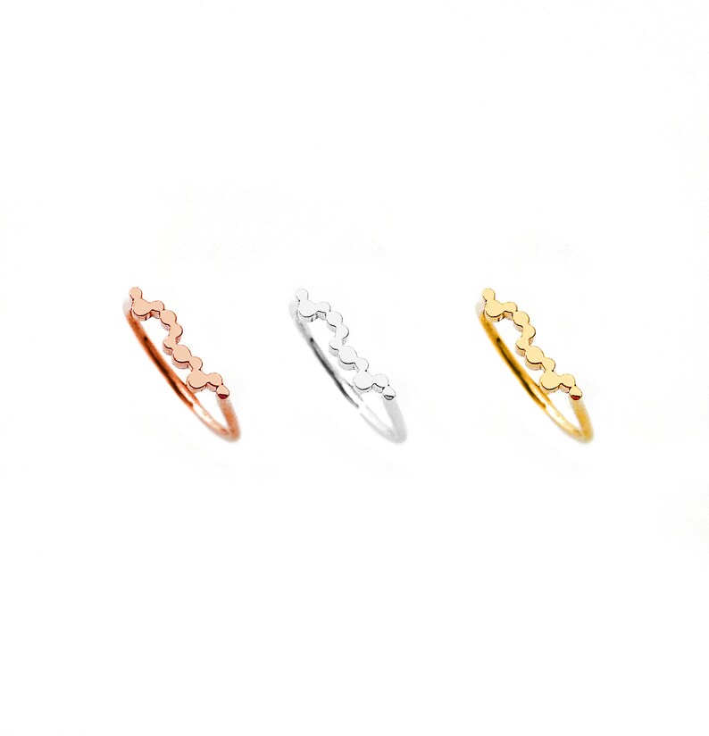 May include: Three delicate rings with a wavy design made of small circles. The rings are in gold, silver, and rose gold.
