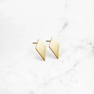 May include: A pair of gold diamond-shaped stud earrings.