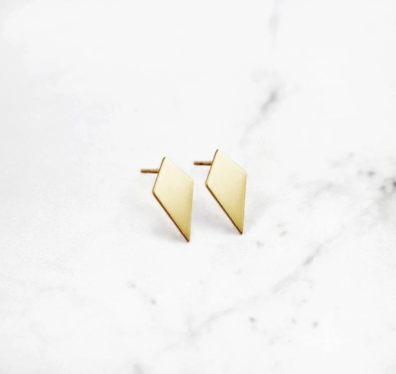 May include: A pair of gold diamond-shaped stud earrings.