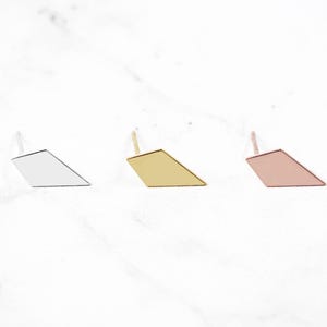 May include: Three diamond-shaped earrings in silver, gold, and rose gold.