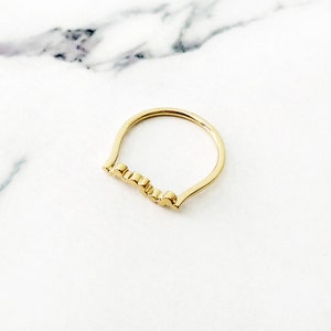 May include: A gold ring with a wavy, textured band.