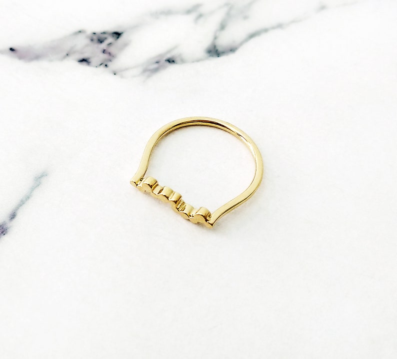 May include: A gold ring with a wavy, textured band.